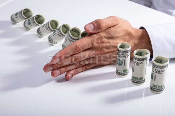 Person Stopping Falling Banknotes On Desk Stock photo © AndreyPopov
