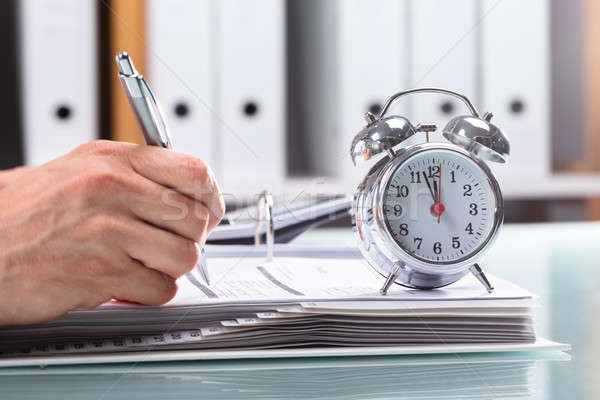 Businessman Working On Document With Alarm Over Desk Stock photo © AndreyPopov