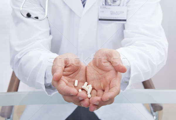 Doctor or male nurse in a white lab coat holding tablets Stock photo © AndreyPopov