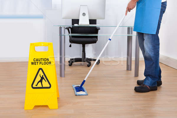 Warning notice as a janitor mops the floor Stock photo © AndreyPopov