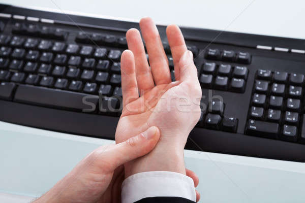 Businessman Holding Painful Wrist At Office Desk Stock photo © AndreyPopov