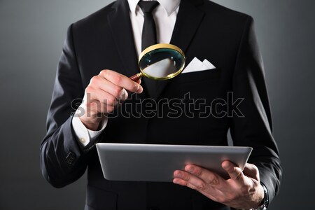Businessman Analyzing Digital Tablet With Magnifying Glass Stock photo © AndreyPopov