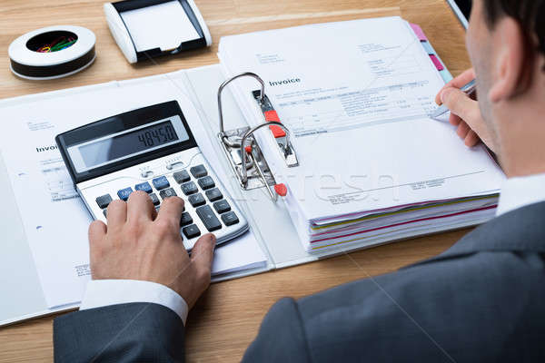 Businessman Calculating Invoice At Office Desk Stock photo © AndreyPopov