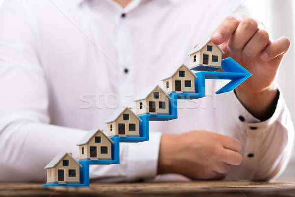 Businessman placing house models on increasing arrow staircase Stock photo © AndreyPopov