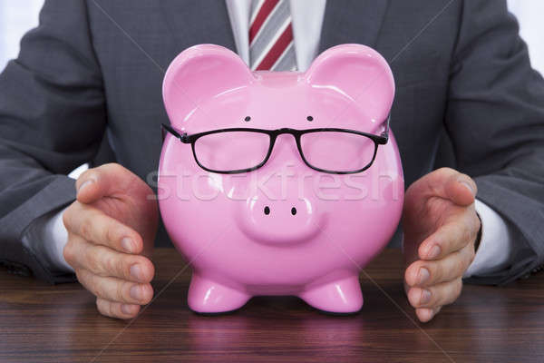 Businessman Shielding Piggybank Wearing Glasses Stock photo © AndreyPopov