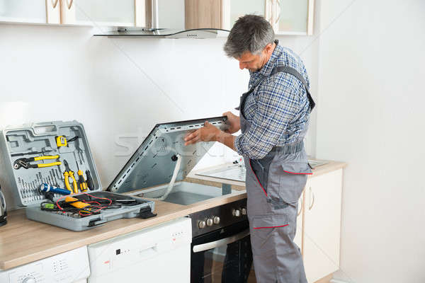 Stock photo: Repairman Examining Stove In Kitchen