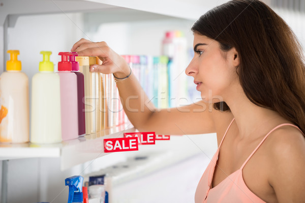Stock photo: Female Customer Selecting Cosmetic Bottle From Shelf