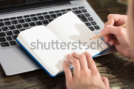 Businessperson Writing On Plain Notebook With Pencil Stock photo © AndreyPopov