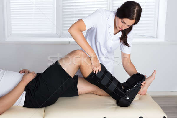 Stock photo: Orthopedist Adjusting Walking Brace On Patient's Leg