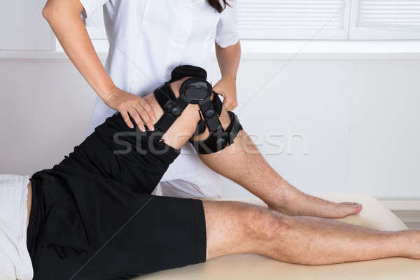 Physiotherapist Fixing Knee Braces On Man's Leg Stock photo © AndreyPopov