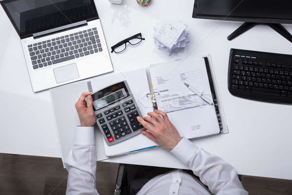 Elevated View Of Businessperson Calculating Invoice Stock photo © AndreyPopov