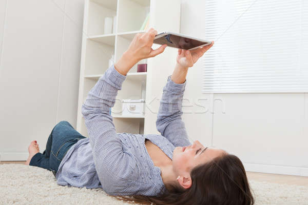 Woman Using Digital Tablet While Lying On Rug Stock photo © AndreyPopov