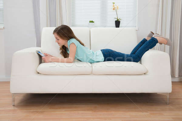 Stock photo: Girl On Sofa Looking At Digital Tablet