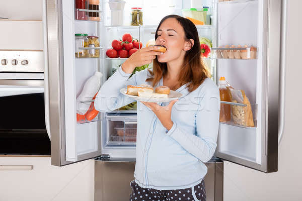 Femme manger aliments sucrés réfrigérateur jeune femme jouir de Photo stock © AndreyPopov