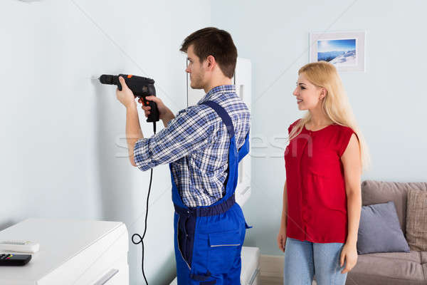 Young Man Using Power Drill On White Wall At Home Stock photo © AndreyPopov