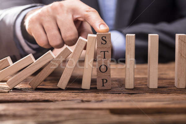 Businessperson's Finger Stopping Falling Dominos Stock photo © AndreyPopov