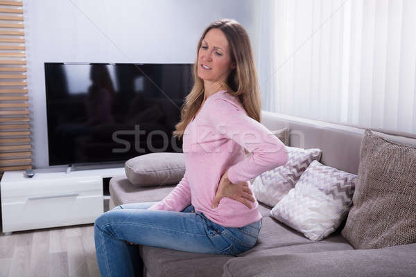 Starsza kobieta cierpienie ból w krzyżu posiedzenia sofa domu Zdjęcia stock © AndreyPopov