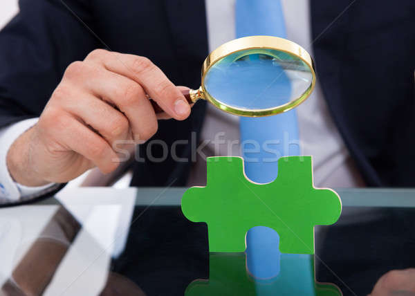 Businessman Scrutinizing Puzzle Piece With Magnifying Glass Stock photo © AndreyPopov