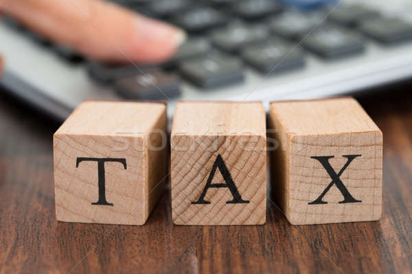 Stock photo: Person Hand Using Calculator With Tax Word On Blocks