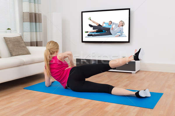 Woman Exercising On Exercise Mat In Front Of Television Stock photo © AndreyPopov