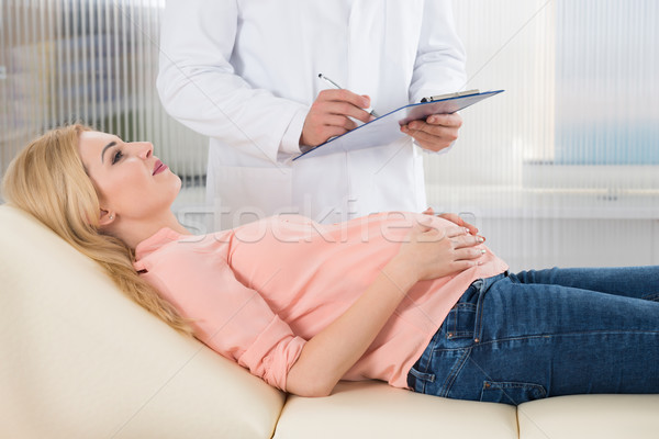 Midsection Of Doctor Writing Notes By Pregnant Woman In Hospital Stock photo © AndreyPopov