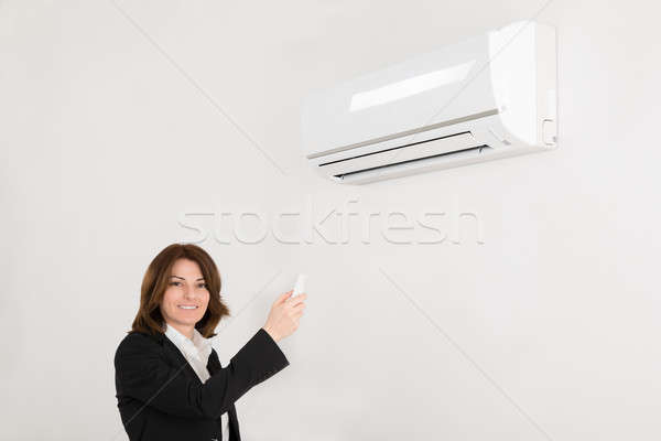 Businesswoman Operating Air Conditioner Stock photo © AndreyPopov