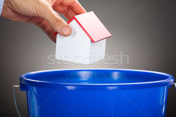 Businessman's Hand Throwing Model Home In Blue Bucket Stock photo © AndreyPopov