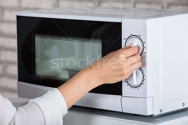 Kobieta mikrofala piekarnik ogrzewania żywności domu Zdjęcia stock © AndreyPopov