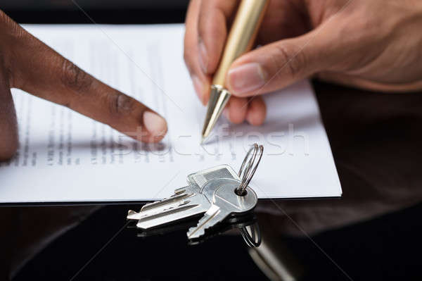 Person's Hand Signing Contract With Keys On It Stock photo © AndreyPopov