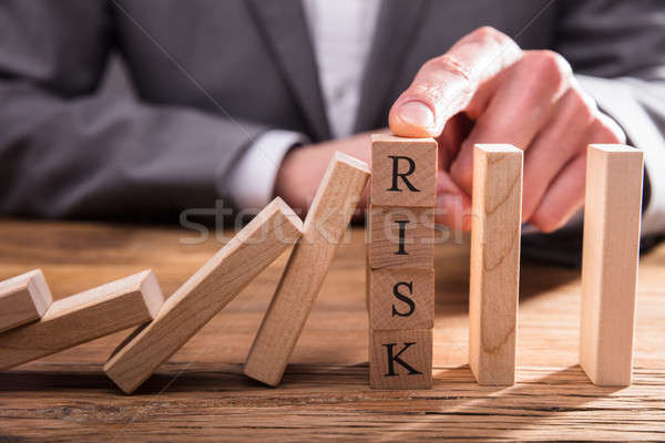 Businessperson's Finger Stopping Dominos From Falling Stock photo © AndreyPopov