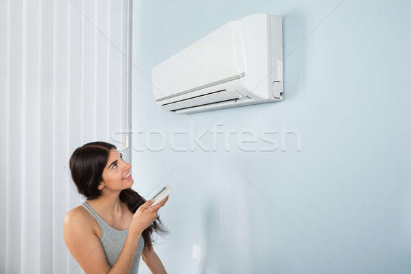 Woman Holding Remote Control Air Conditioner Stock photo © AndreyPopov