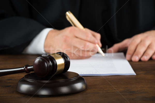 Stock photo: Judge Writing On Legal Documents At Desk