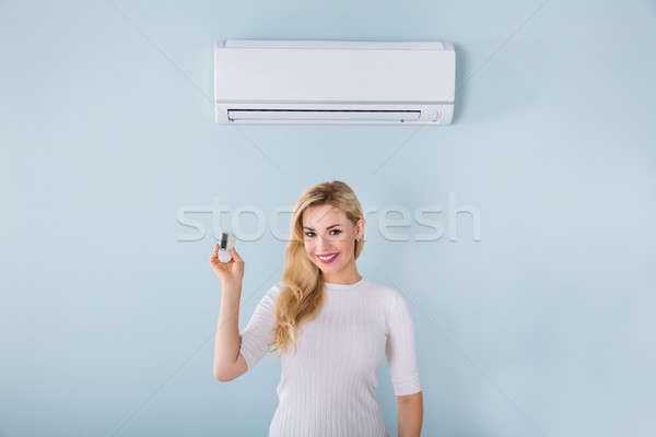 Vrouw afstandsbediening airconditioner portret glimlachend Stockfoto © AndreyPopov