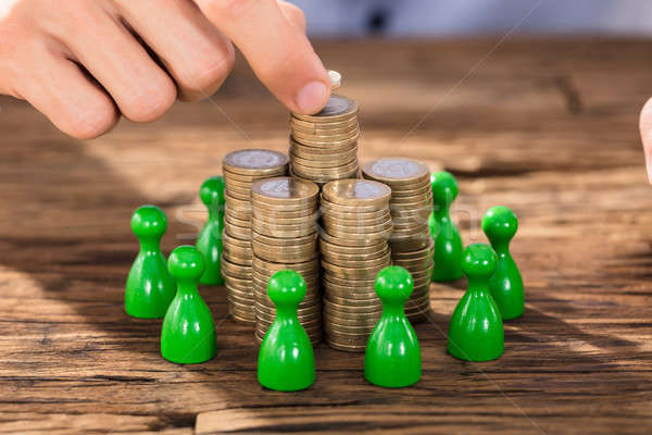 Businessman Placing Coins Over Stack With Green Figures Stock photo © AndreyPopov