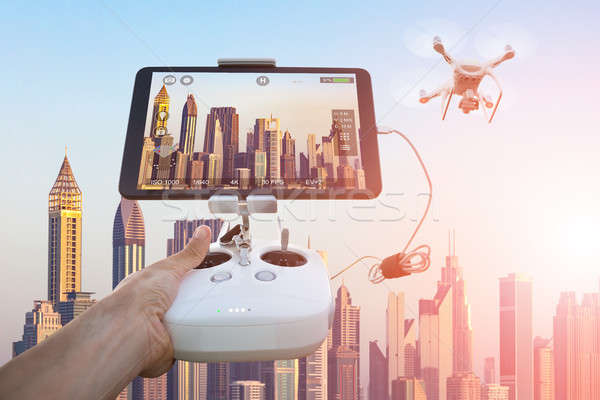 Hand controlling drone filming cityscape during sunset Stock photo © AndreyPopov