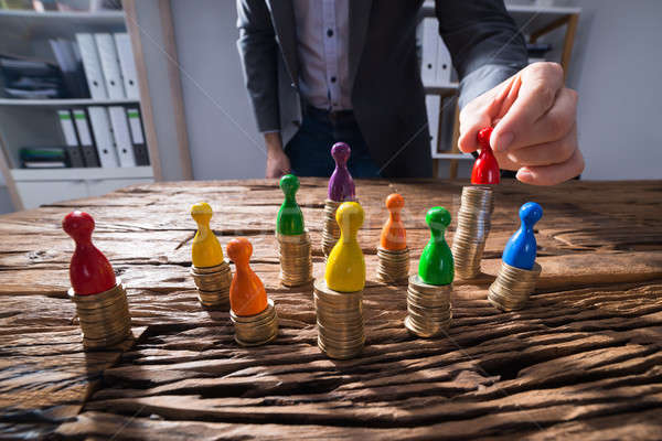 Businessperson Placing Red Figurine Pawn On Stacked Golden Coins Stock photo © AndreyPopov
