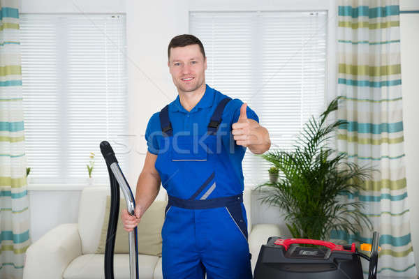 Janitor Showing Thumbs Up While Holding Vacuum Cleaner At Home Stock photo © AndreyPopov