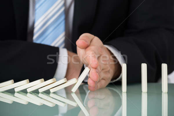 Businessperson Stopping Dominos Falling On Desk Stock photo © AndreyPopov
