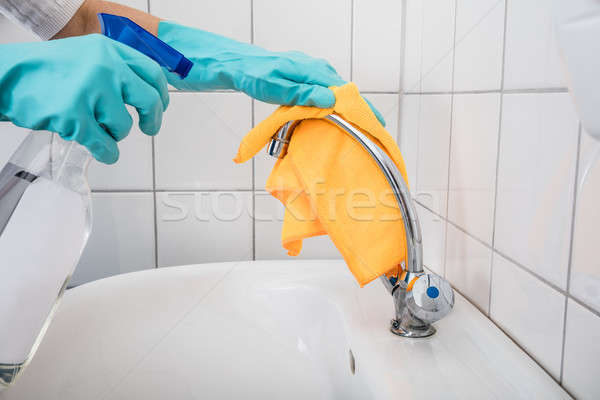 Stock photo: Person Cleaning Faucet In Bathroom