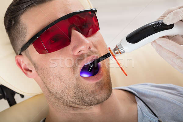 Man's Teeth Are Treated By Lit Dental Curing UV Light Stock photo © AndreyPopov
