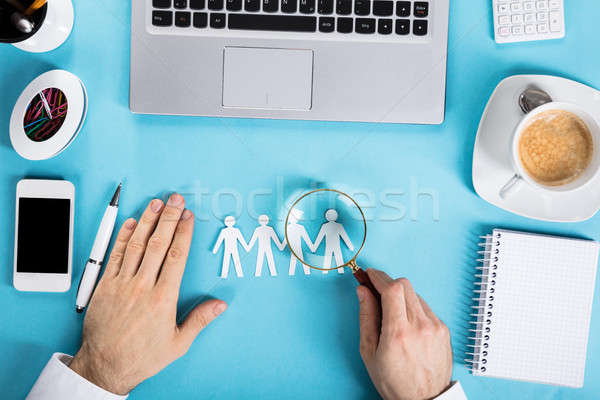 Businessman Magnifying The Paper Cut Out Human Figure Stock photo © AndreyPopov