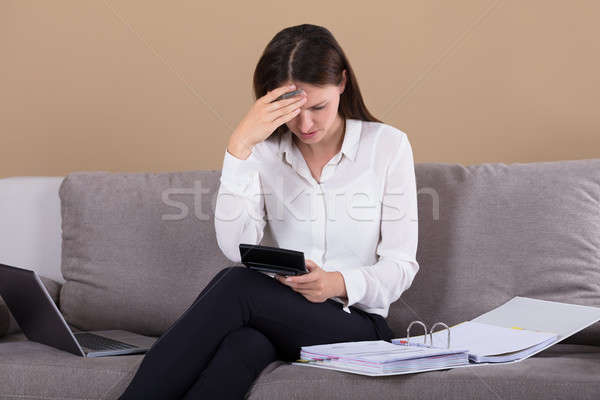 Woman Sitting On Sofa Holding Calculator Stock photo © AndreyPopov