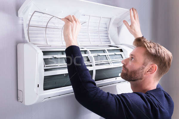 Young Man Checking Air Conditioner Stock photo © AndreyPopov