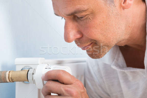 Stock photo: Man Adjusting Temperature Of Radiator Thermostat