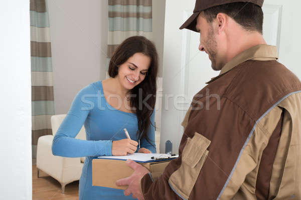 Young Woman Signing While Receiving Courier Stock photo © AndreyPopov