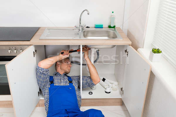 Vízvezetékszerelő javít mosdókagyló konyha fiatal férfi Stock fotó © AndreyPopov