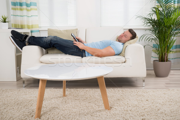Om Control de la distanţă dormit canapea acasă Imagine de stoc © AndreyPopov