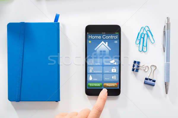 Woman Using Home Control Application On Mobile Phone Stock photo © AndreyPopov