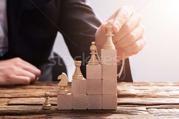 Businessperson Arranging Chess Piece On Wooden Blocks Stock photo © AndreyPopov