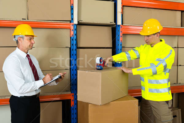 Manager With Clipboard And Worker Taping Box Stock photo © AndreyPopov